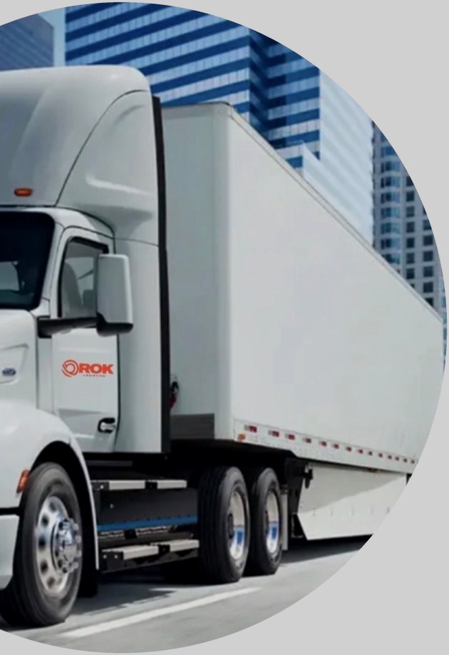 White Orok Logistics truck with a 53-foot dry van trailer in front of city buildings